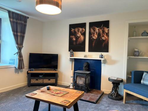 a living room with a table and a fireplace at POSTBOX CROFT With A Sea View in Armadale