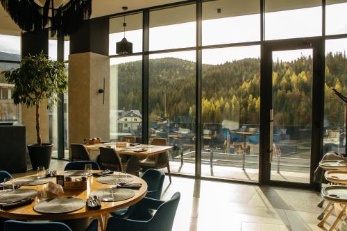 Rest&Ski Spa Resort في بوكوفِل: مطعم بطاولات وكراسي ونوافذ كبيرة