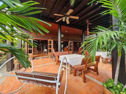 eine Terrasse mit Tischen und Stühlen und einem Deckenventilator in der Unterkunft The Thai House Homestay & Thai Cooking Experiences in Ban Bang Sano