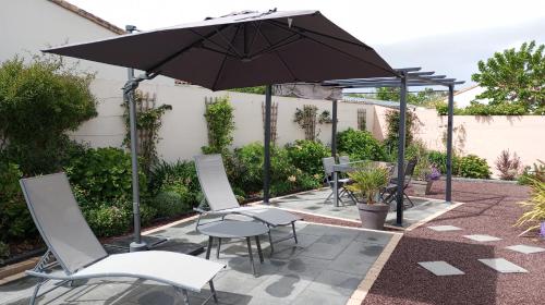 un patio avec une table, des chaises et un parasol dans l'établissement Jolie maison au calme - 300m de la plage - Terrasse - Barbecue, à Saint-Michel-Chef-Chef