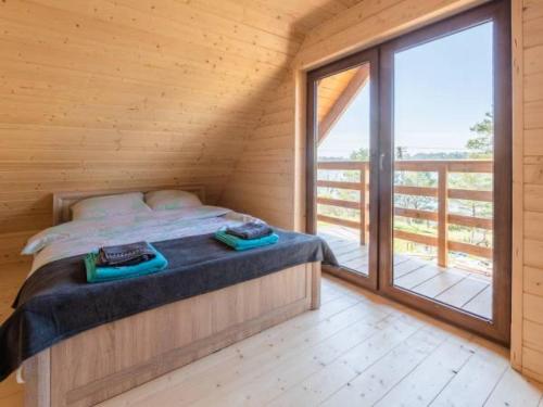a bedroom with a bed and a large window at Karmelowe Domki Kaszuby, 80m do jeziora in Stężyca