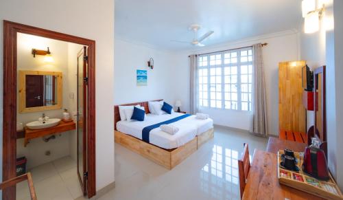 a bedroom with a bed and a sink and a mirror at Biosphere Inn in Dharavandhoo