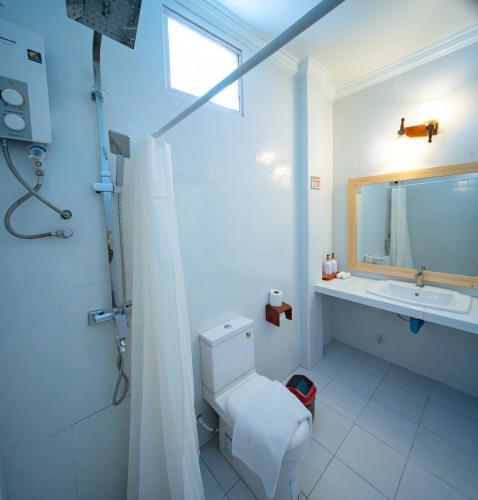 a white bathroom with a toilet and a sink at Biosphere Inn in Dharavandhoo
