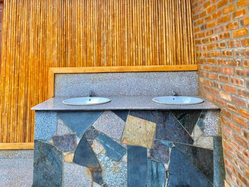 um balcão de pedra com dois lavatórios numa parede de tijolos em Tuan Ngoc Hotel em Ninh Binh