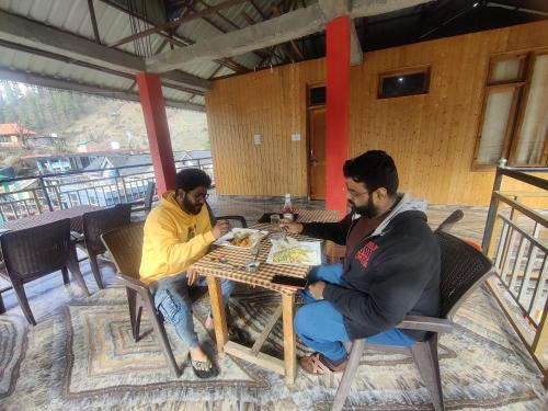 Dois homens sentados numa mesa a jogar um jogo de tabuleiro. em SURAJ GUEST HOUSE TOSH em Tosh