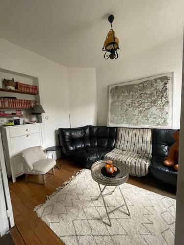 Maison 20 min de PARIS : غرفة معيشة مع أريكة جلدية سوداء وطاولة
