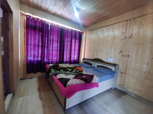 um quarto com uma cama e uma janela com cortinas roxas em SURAJ GUEST HOUSE TOSH em Tosh