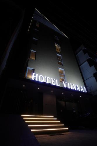 a hotel building with a lit up sign at night at HOTEL VILVAAS in Madurai