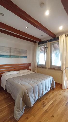 a large bed in a bedroom with two windows at Parma Country Room in Montechiarugolo