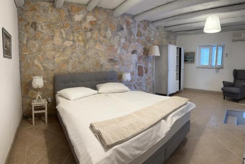 a bedroom with a large bed and a stone wall at Villa Viden Apartments in Tučepi