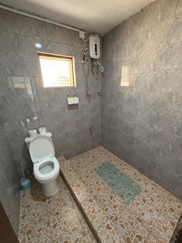 a bathroom with a toilet and a window at Beautiful house in Oxford street KFC in Accra