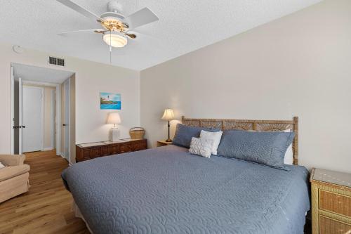 a bedroom with a blue bed and a ceiling fan at Sea Coast Gardens II 316 in New Smyrna Beach