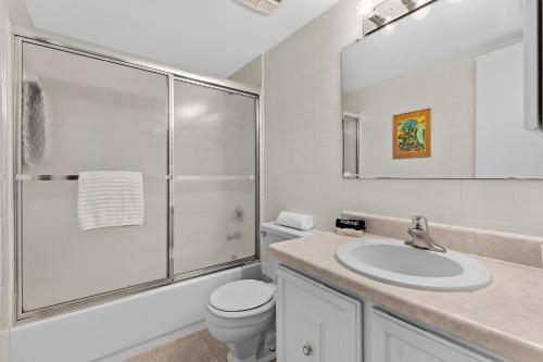 a white bathroom with a toilet and a sink at Sea Coast Gardens II 316 in New Smyrna Beach