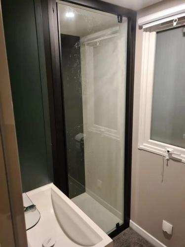 une salle de bain avec une douche avec une porte vitrée dans l'établissement Chez Boby !, à Canet