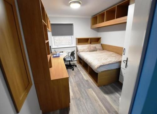 um pequeno quarto com uma cama e uma secretária em Plas Gwyn Halls, Cardiff Met University em Cardiff