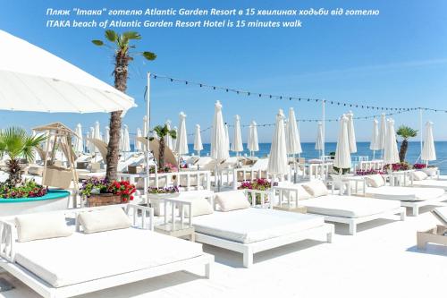 un gruppo di sedie a sdraio e ombrelloni bianchi sulla spiaggia di Atlantic Garden Resort a Odessa