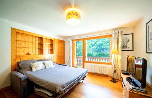 une chambre avec un lit, une télévision et une fenêtre dans l'établissement Bozel Rez de Chausse T1, à Bozel