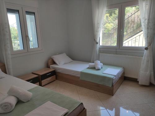 Un dormitorio con dos camas y dos ventanas. en Capital Apartment Iraklitsa, en Nea Iraklitsa