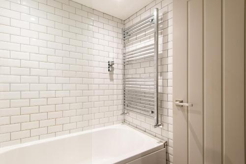 y baño de azulejos blancos con bañera y ducha. en Beautiful, central, 3 min walk from beach, 2 King doubles en Brighton & Hove