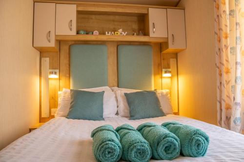 a bed with a bunch of green pillows on it at Lake View with Private Hot Tub at Tattershall Lakes in Tattershall