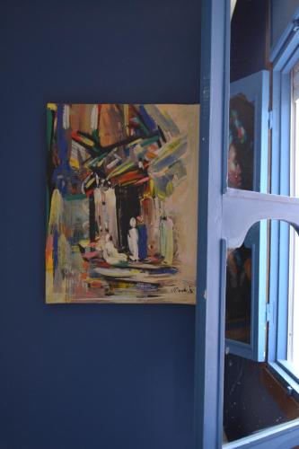 a painting hanging on a wall next to a window at Playa Del Sol Surf House in Tamraght Ouzdar
