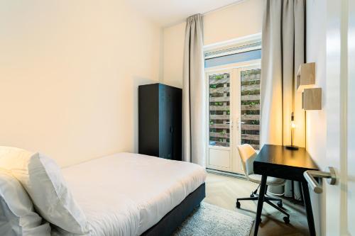 a bedroom with a bed and a desk and a window at Stylish apartment next to the Amstel River - Unit C in Amsterdam
