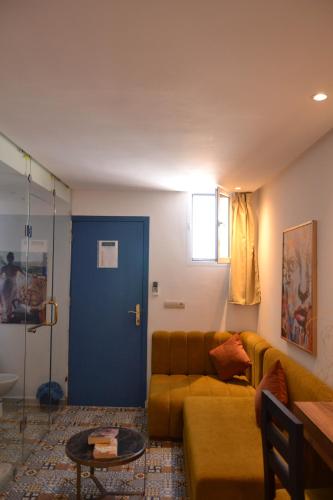 a living room with a couch and a blue door at Playa Del Sol Surf House in Tamraght Ouzdar