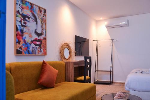 a living room with a couch and a bed and a desk at Playa Del Sol Surf House in Tamraght Ouzdar