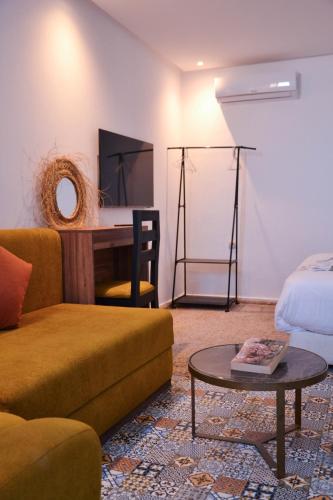 a living room with a couch and a table and a bed at Playa Del Sol Surf House in Tamraght Ouzdar