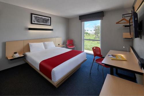 een hotelkamer met een bed, een bureau en een raam bij City Express by Marriott Monterrey Norte in Monterrey
