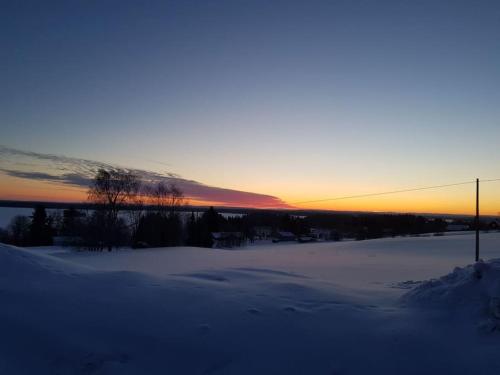 a snowy field with a sunset in the background at Lake view house in Hammerdal in Hammerdal