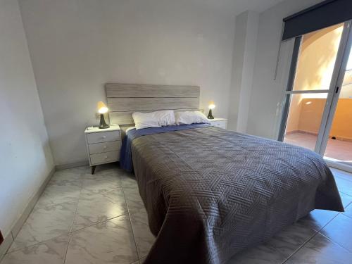 um quarto com uma cama com duas mesas de cabeceira e uma janela em Casa adosada junto a la playa de El Perelló em Sueca