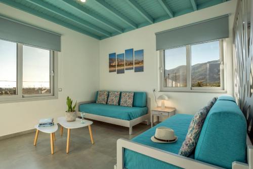 a living room with a blue couch and windows at Paradisos in Frangokastello