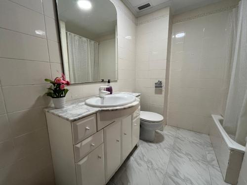 biała łazienka z umywalką i toaletą w obiekcie Casa adosada junto a la playa de El Perelló w mieście Sueca