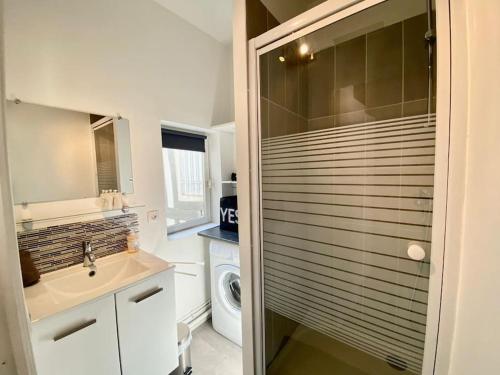 La salle de bains est pourvue d'un lavabo et d'une porte de douche en verre. dans l'établissement Charmant studio plein centre historique - 071, à Rouen