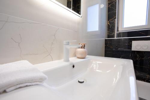 un lavandino bianco in bagno con un vaso sopra di Seaside residence - Sunset Appartement a Kožino