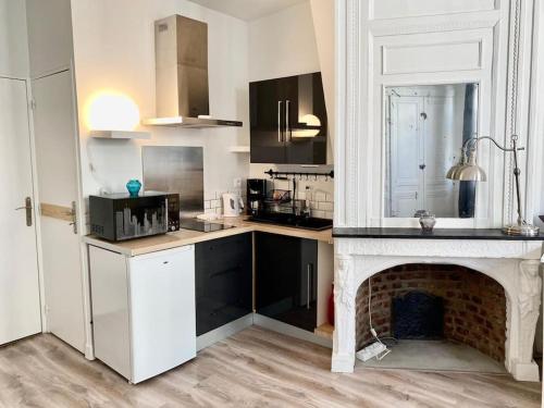 une cuisine avec une cheminée et un comptoir blanc dans l'établissement Charmant studio plein centre historique - 071, à Rouen