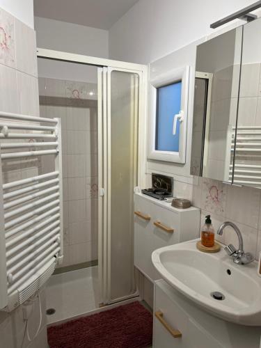 a white bathroom with a sink and a shower at La petite maison de la gare in Nemours