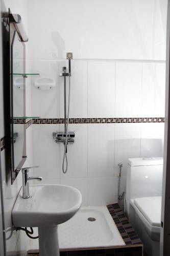 a white bathroom with a sink and a toilet at Hôtel Les 12 Collines, Ivato Aéroport in Ambohijanahary