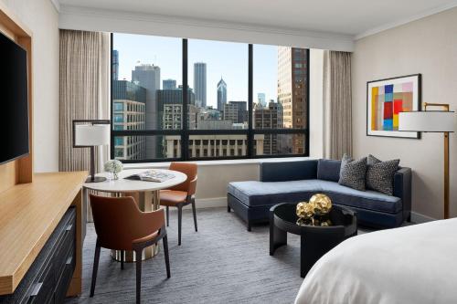 シカゴにあるザ リッツ カールトン シカゴのベッド、ソファ、テーブルが備わるホテルルームです。