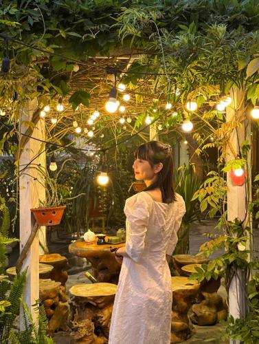 a woman in a white dress standing in a garden at Love House Homestay SAPA in Sa Pa