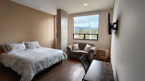 a bedroom with a bed and a chair and a window at La Milla, Lofts in Chía