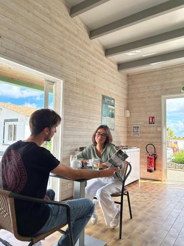 un homme et une femme assis à une table dans l'établissement Campiotel Les Dunes - ROMANEE, à Ars-en-Ré