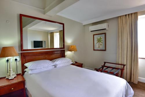 a bedroom with a large white bed and a mirror at The Balmoral in Durban