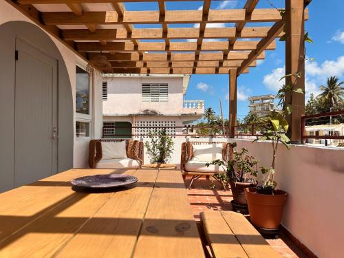 een patio met een houten tafel en een houten pergola bij Sonsoleá in Luquillo