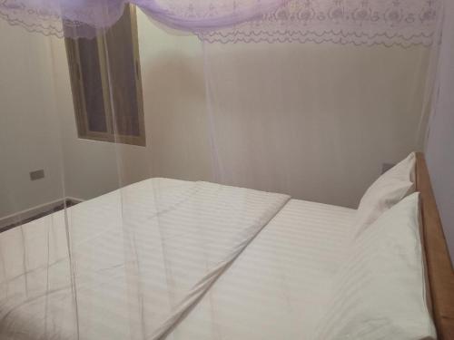 uma cama branca num quarto com uma janela em Grand Grove Villa em Jinja