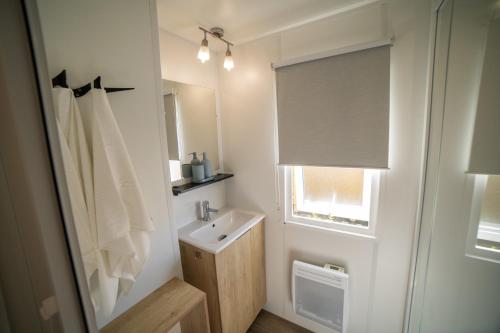 a white bathroom with a sink and a window at La Belle au Bois Normand in Litteau