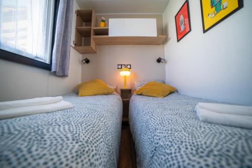 two twin beds in a small room with a lamp at La Belle au Bois Normand in Litteau
