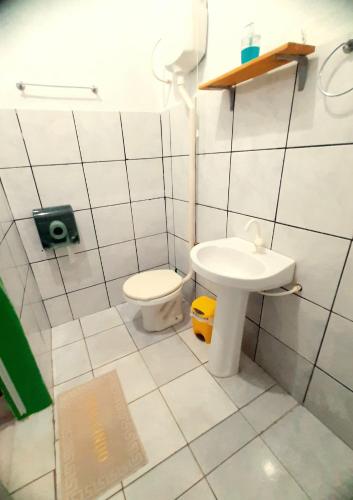 a white bathroom with a toilet and a sink at Hospedagem Jabuti no Centro de São Jorge in Sao Jorge
