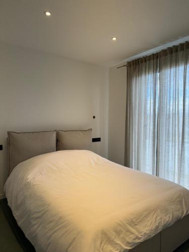 - un lit blanc dans une chambre avec fenêtre dans l'établissement Spatieux T3 60m2 Annecy - Parking Privé - WIFI - Netflix, à Annecy